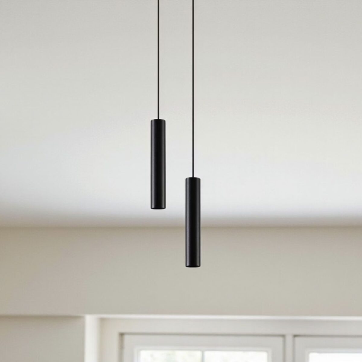 Zwei schwarze Röhrenpendelleuchten auf unterschiedlicher Höhe vor einer hellen Wand