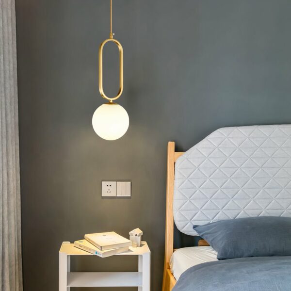 Goldene Hängeleuchte aus Glasstein in modernem Design auf grauem Hintergrund mit einem Bett auf der rechten Seite