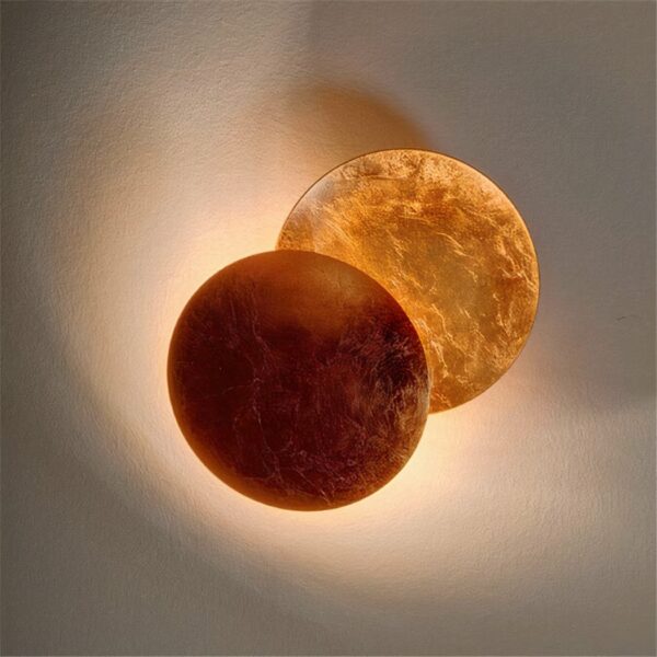 Auf einem weißen Hintergrund sehen Sie eine Wandleuchte in Form einer braunen Mondfinsternis, die eingeschaltet ist.