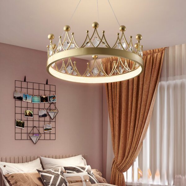 Kronleuchter für das Babyzimmer in Form einer goldfarbenen Krone mit Kristallsteinen in einem Zimmer mit rosafarbenen Wänden