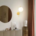 In einem Wohnzimmer hängt eine Wandleuchte in modernem, goldenem Stil an der Wand.