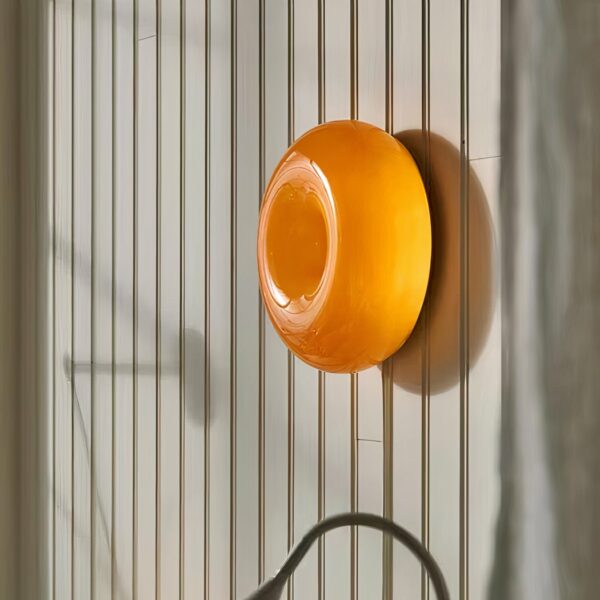 Orangefarbene, runde Wandleuchte, an einer Wand positioniert