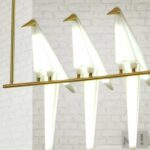 Origami-Vogel-Pendelleuchten eingeschaltet vor einer weißen Ziegelwand