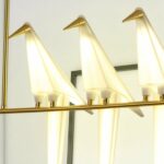 Nahaufnahme der leuchtenden Origami-Vogel-Schirme an einer goldenen Leuchtenstange