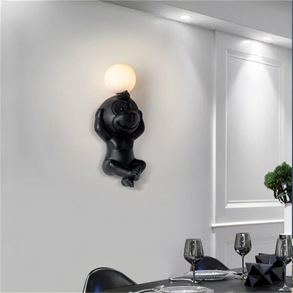 Auf einer dunkelblauen Wand sehen Sie in der Mitte eine eingeschaltete weiße Wandleuchte in Form eines Affen hängen.