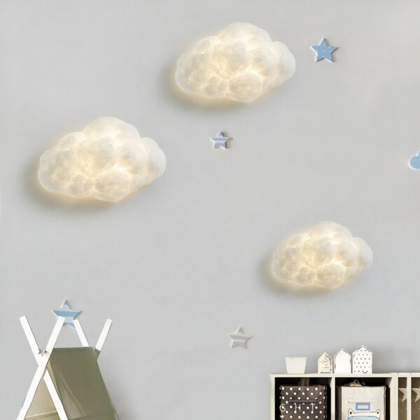 Auf einer weißen Wand sehen Sie drei weiße wolkenförmige Wandleuchten, die eingeschaltet sind.
