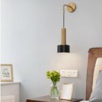 Wandleuchte aus Messing im Laternenstil, schwarz und goldfarben, hängt neben einem Bett