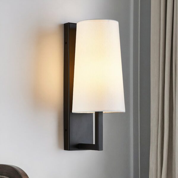 Wandleuchte aus Stoff auf schwarzem Träger, mit eingeschaltetem Licht, an einer Wand