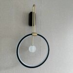 Vorderansicht der schwarzen Ring-Wandleuchte mit goldenem Rahmen und kleiner Glaskugel, ausgeschaltet
