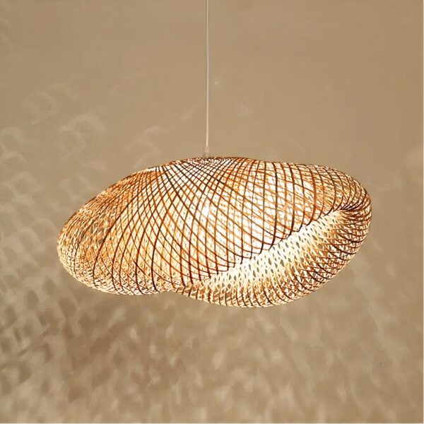 Kronleuchter en bambou à grand abat-jour aéré au design moderne. Avec l'ampoule allumée, qui projette des ombres sur le mur beige derrière le lustre.