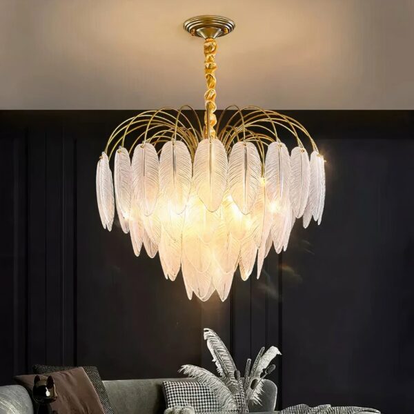 Kronleuchter plumes en verres en forme de grappe. Allumé et installé dans un salon avec le mur du fond noir et un canapé gris. Le plafond est blanc et on voit le reflet de la lumière dessus.