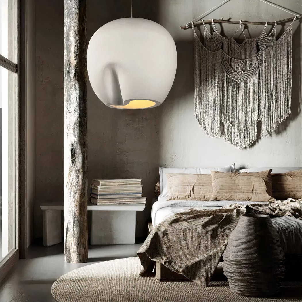 Organisch geformte helle Keramik-Pendelleuchte über einem Bett in einem Boho-Schlafzimmer