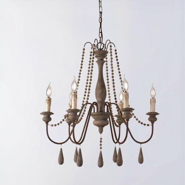 Kronleuchter en laiton et bois avec 6 chandelles, les ampoules remplacent la flemme des bougies. Décorées de perles, des allongées qui se trouvent sous chaque chandelle et des plus petites sur le reste du lustre. Sur un fond gris.