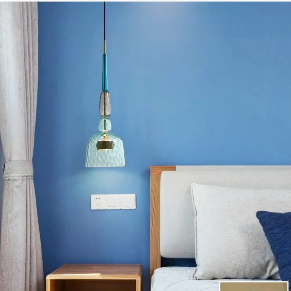Kronleuchter suspendu LED moderne en verre coloré sur fond bleu avec un lit à droite
