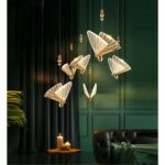 in einem dunkelbraun-grünen Wohnzimmer sehen Sie eine goldene, transparente Hängeleuchte in Form eines Schmetterlings