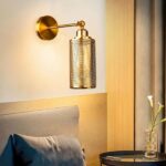 in einem Schlafzimmer sehen Sie über einem Bett eine goldene Wandleuchte im Industriestil