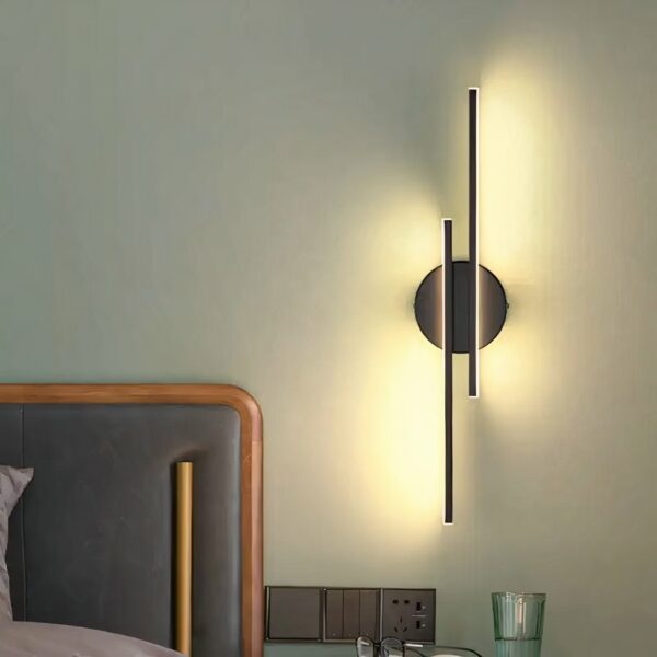 Lineare Wandleuchte in modernem Design, die an der Wand eines Schlafzimmers hängt und eingeschaltet neben dem Bett hängt.