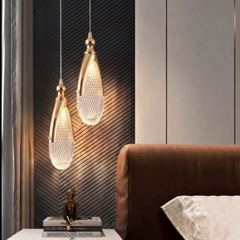Pendelleuchte mit flachen Tropfen aus geschliffenem Acryl und goldener Fassung im Schlafzimmer