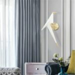 in einem grauen Wohnzimmer sehen Sie eine Origami-Wandleuchte in Form eines Vogels in Weiß und Gold