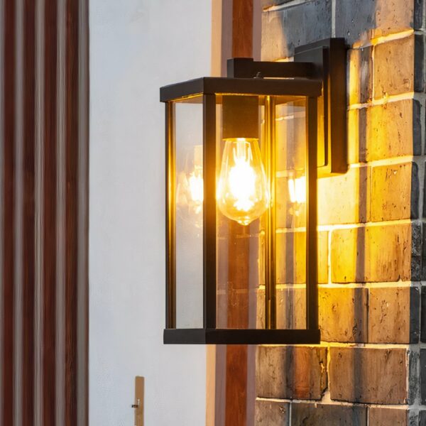 Retro-Außenwandleuchte aus Aluminium und Glas, die an einer gemauerten Außenwand hängt und beleuchtet ist.