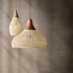 Zwei naturfarbene Bambus-Pendelleuchten mit Holzspitze in unterschiedlicher Form vor einfacher Wand