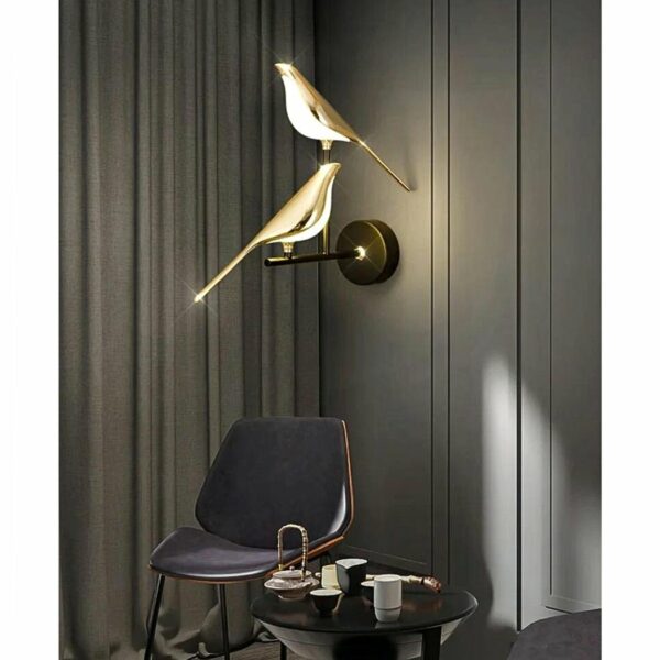 in einem dunkelgrauen Wohnzimmer sehen Sie eine Wandleuchte mit einem Vogelduo, das wie auf einem goldenen Ast sitzt
