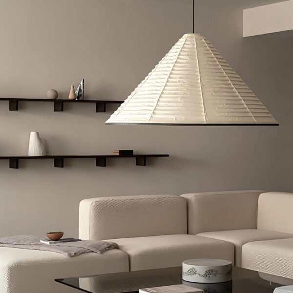 Suspension en papier japonais en forme de cône beige dans un salon avec un canapé d'angle beige. A l'arrière des étagères marron sont fixées sur le mur.