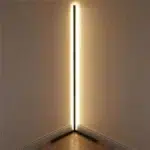 Lampadaire d’angle LED intelligent connecté, design minimaliste noir, lumière RGB personnalisable, installé dans l'angle d'une chambre face à un mur, réfléchissant ainsi son halo de lumière.