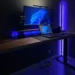 Violett leuchtende Eckstehleuchte und LED-Lichtleiste über dem Monitor am Schreibtisch