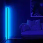 Blau leuchtende LED-Eckstehleuchte neben einem Sofa in dunklem Wohnzimmer