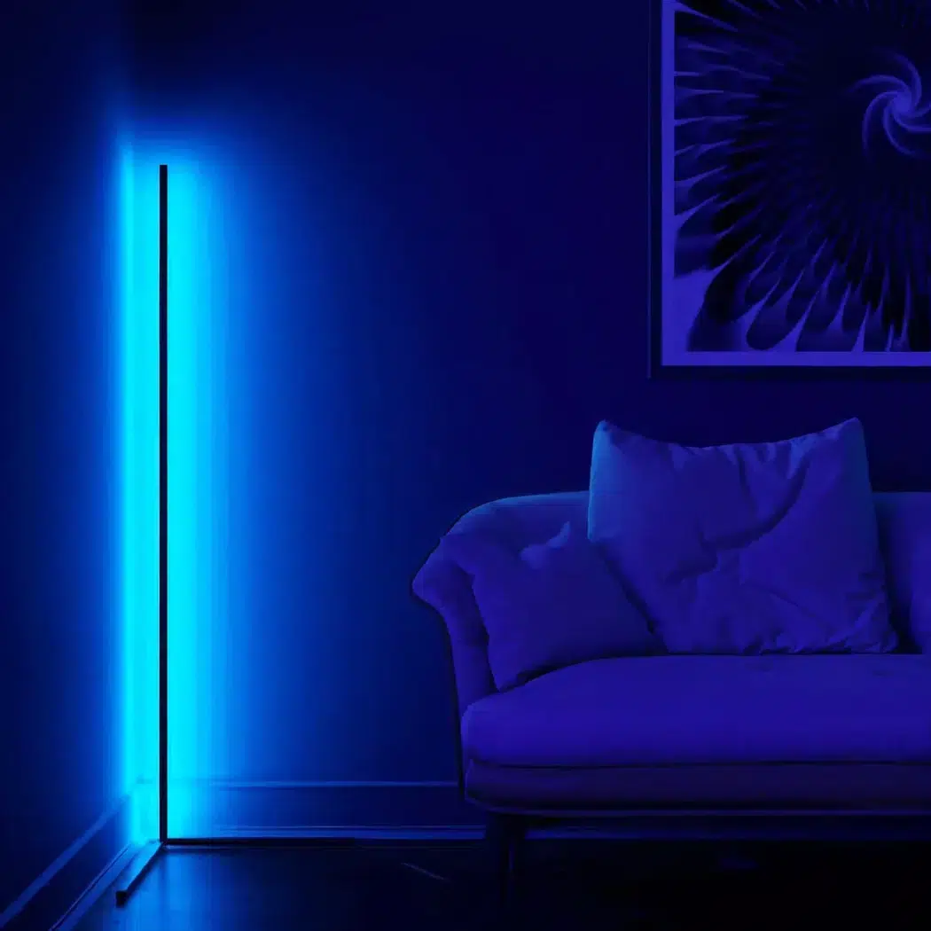 Blau leuchtende LED-Eckstehleuchte neben einem Sofa in dunklem Wohnzimmer