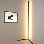 Schwarze Eck-Stehleuchte mit warmweißem Licht neben einem abstrakten Wandbild