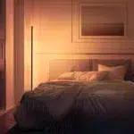 Warmweiß leuchtende Eck-Stehleuchte neben dem Bett in einem gemütlichen Schlafzimmer