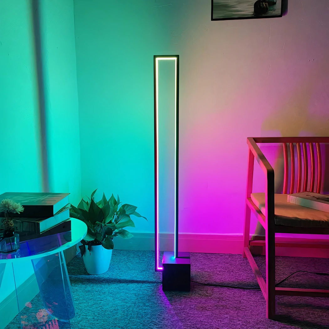 LED-Eckstehleuchte in Türkis und Pink neben gestreiftem Sessel