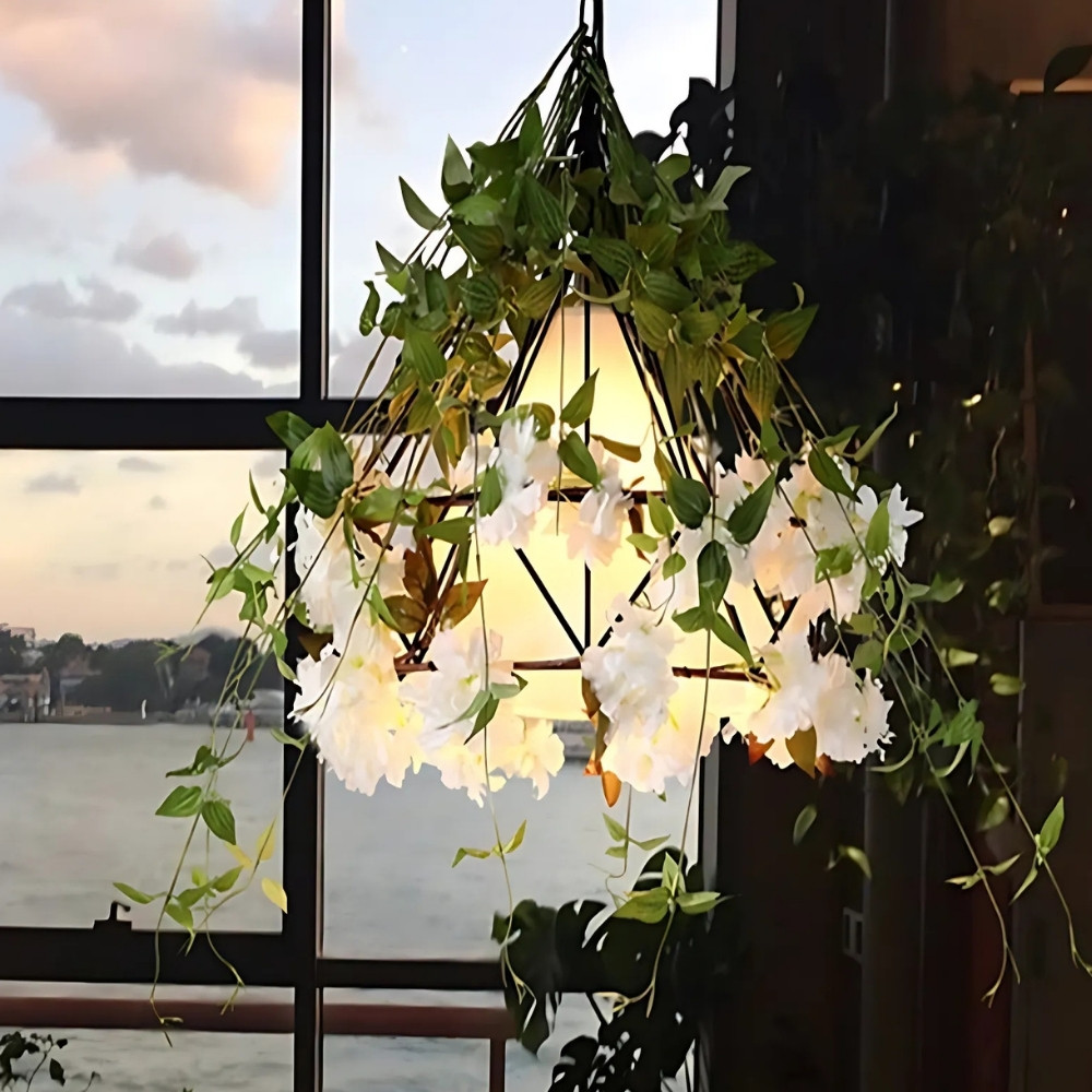 Kegelförmige Pendelleuchte mit weißen Blüten und Blattranken vor einem Fenster mit Meerblick