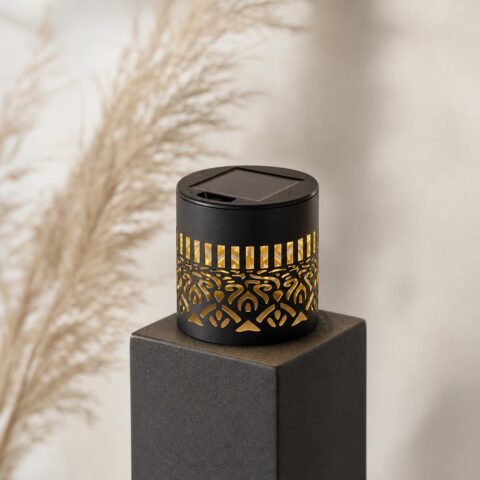 Kleine schwarze Solarleuchte mit goldenem Mandala-Ausschnitt auf einem Sockel